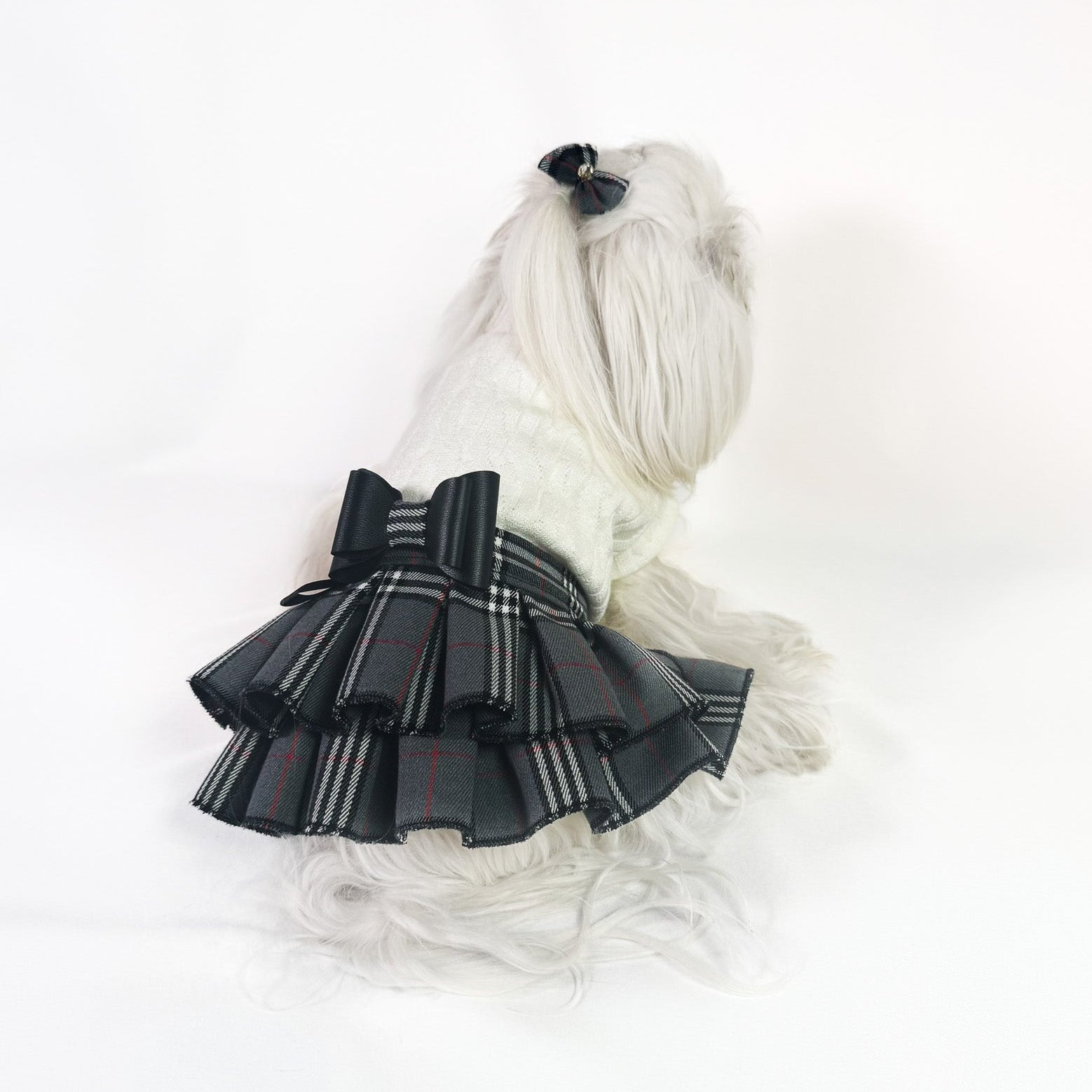Abito per cane di piccola taglia con maglia panna a collo alto e gonna a balze in tessuto scozzese grigio con fiocco nero centrale