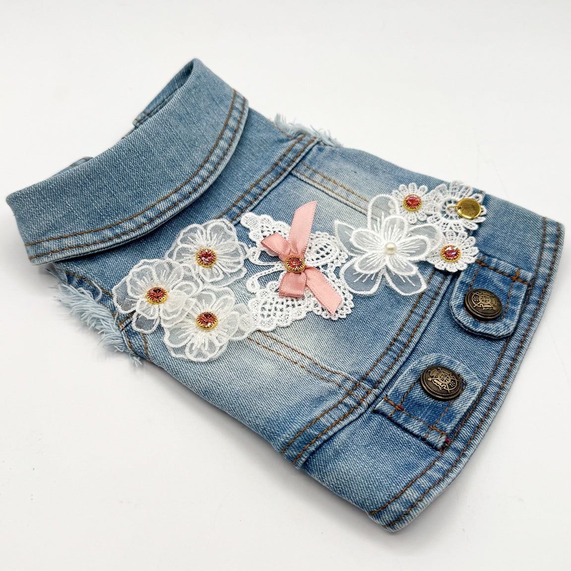 Dettaglio BauJeans Clarisse in jeans light con ricami applicati a mano e fiocco rosa