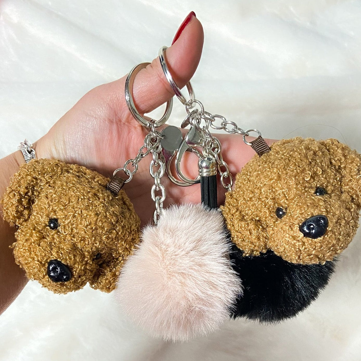 Charms Barboncino in teddy caramello con ponpon rosa e nero tenuti in mano