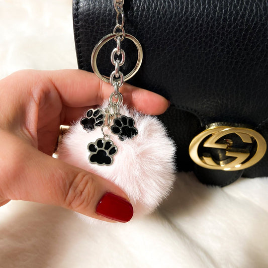 Charms con ponpon chiaro e ciondoli a zampina color nickel appeso a una borsa