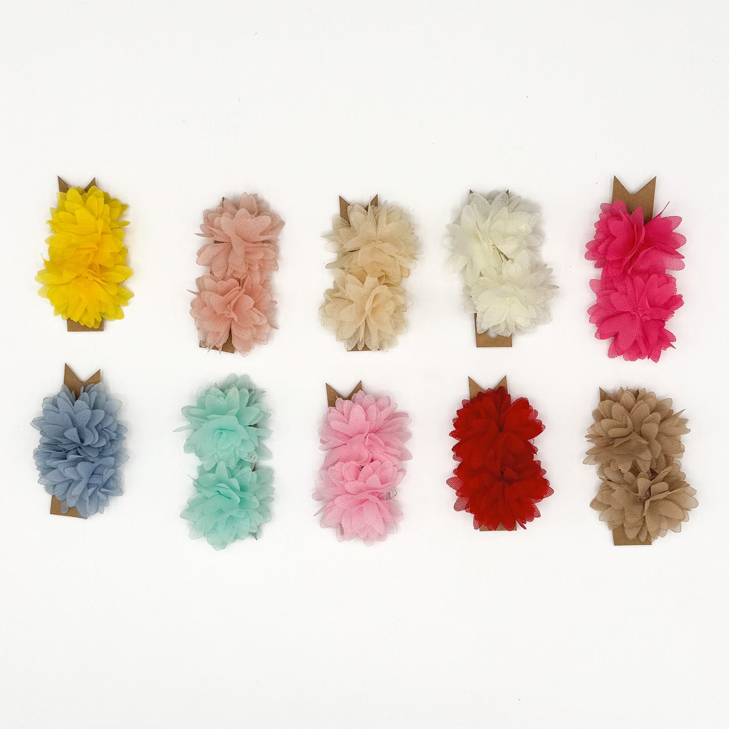 Fermagli a fiore per cani piccoli in tulle, i dieci colori disponibili disposti su fondo bianco
