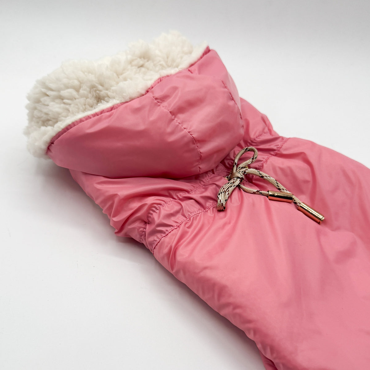 Dettaglio del parka rosa per cani piccoli: coulisse con cordoncino e puntali dorati, interno in teddy panna